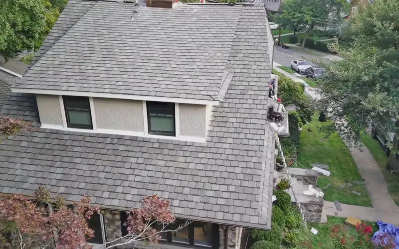 Traditional shingle roof with a crew member working along its edge